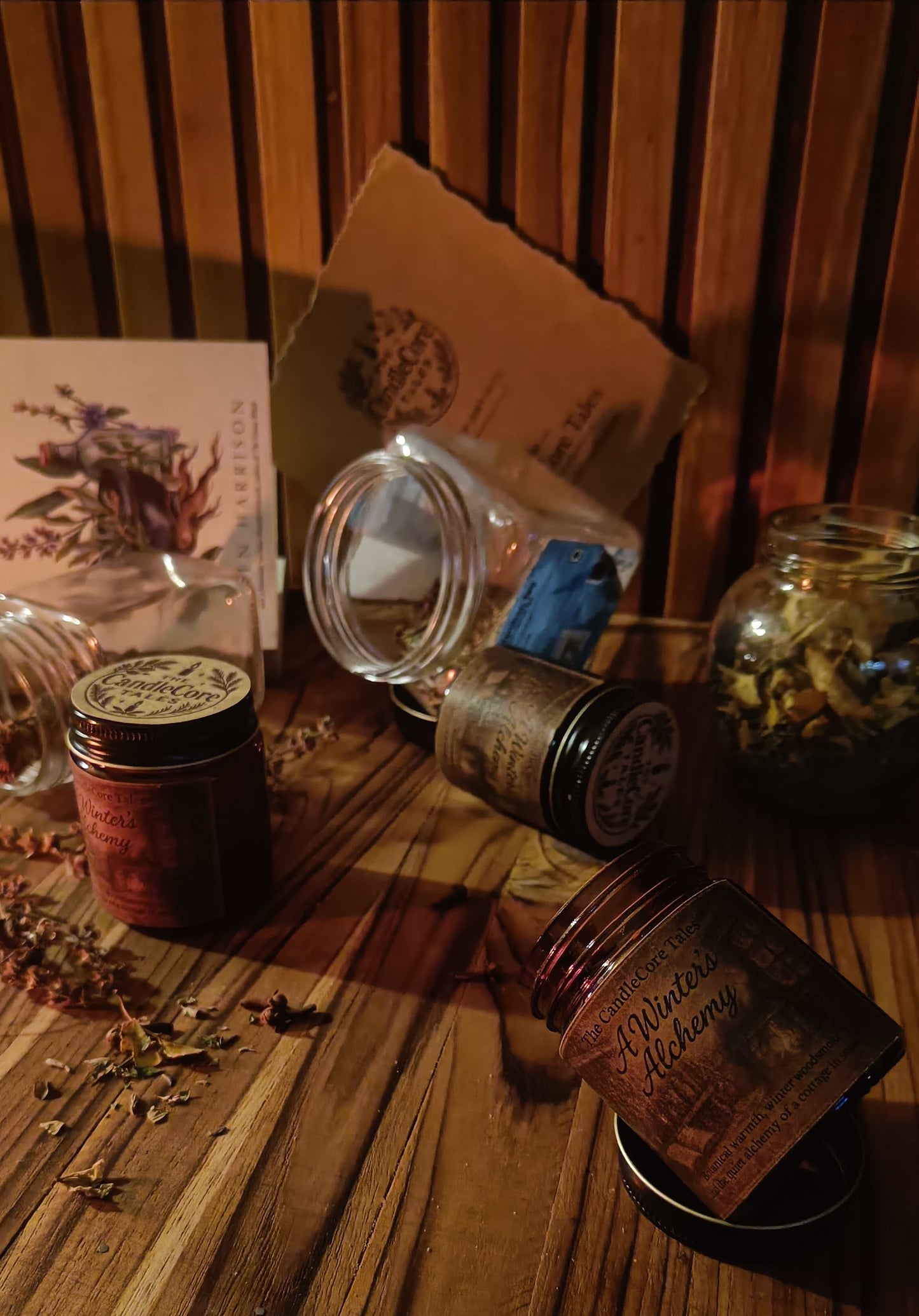 A Winter's Alchemy soy candle arranged in warm firelight on a wooden surface, evoking a cosy cottagecore winter hearth setting.